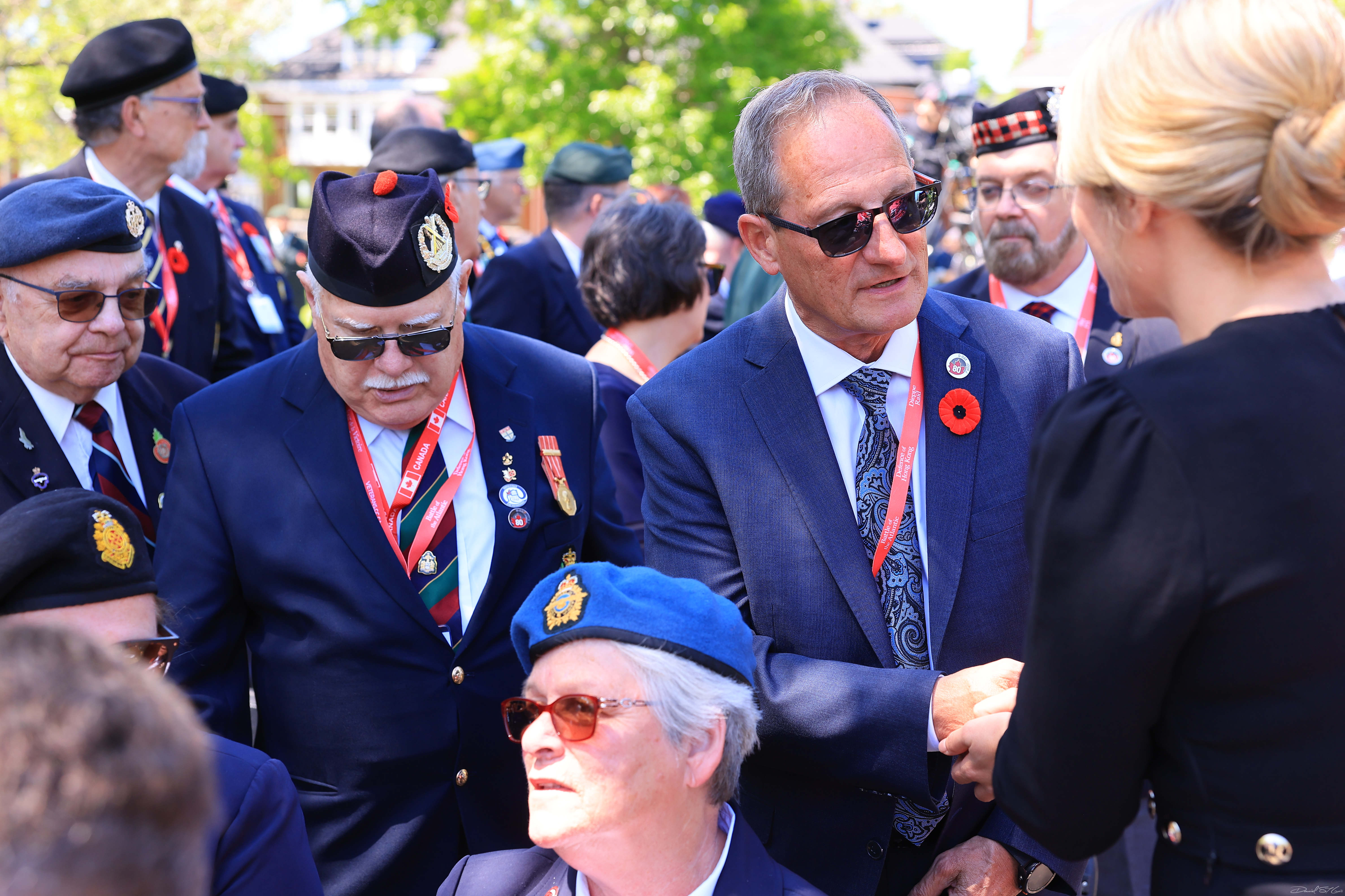  Veterans Review and Appeal Board Deputy Chairperson Jacques Bouchard in a crowd with Veterans and shaking the hand of a blond woman.