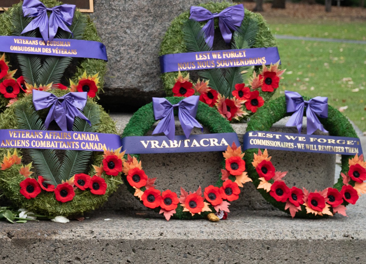 A wreath at a Remembrance Day ceremony with a purple banner that reads “VRAB/TACRA”.